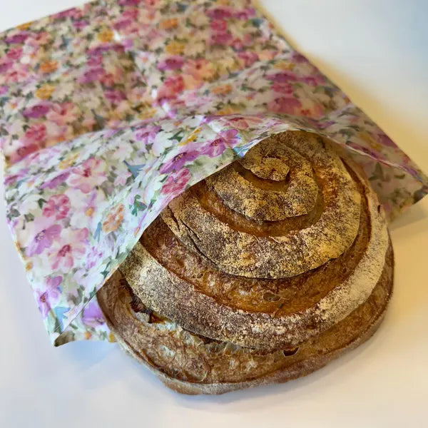 Loaf of sourdough bread wrapped in a floral beeswax cotton bag