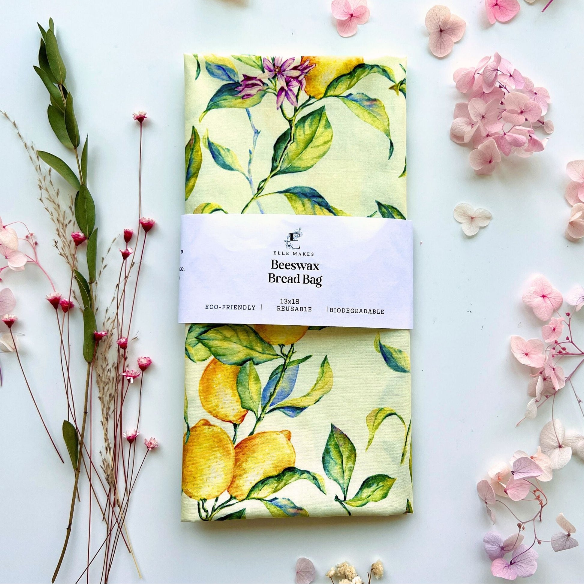 Beeswax bread bag with bright lemon branch design on a white background with flowers and leaves.