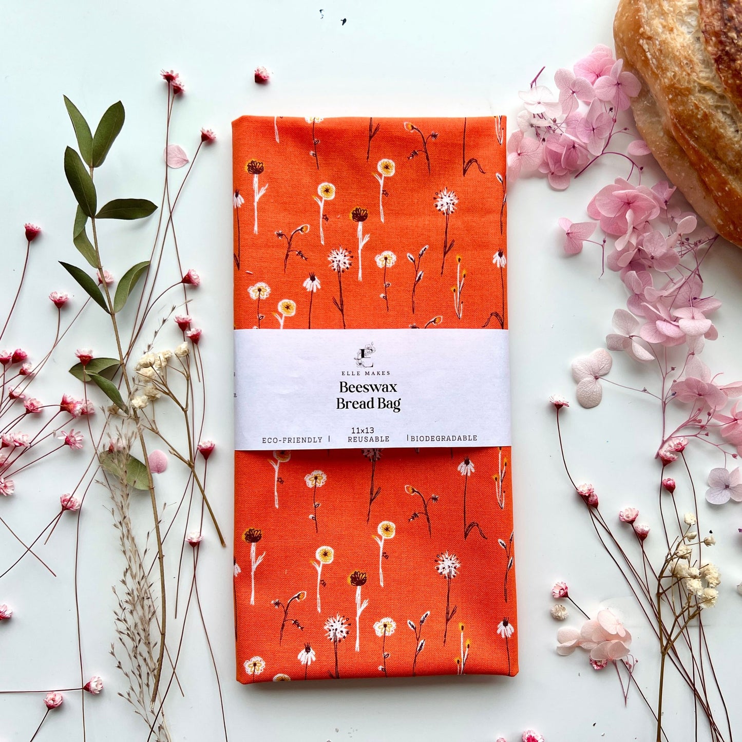 Beeswax bread bag with white floral pattern on orange cotton fabric.