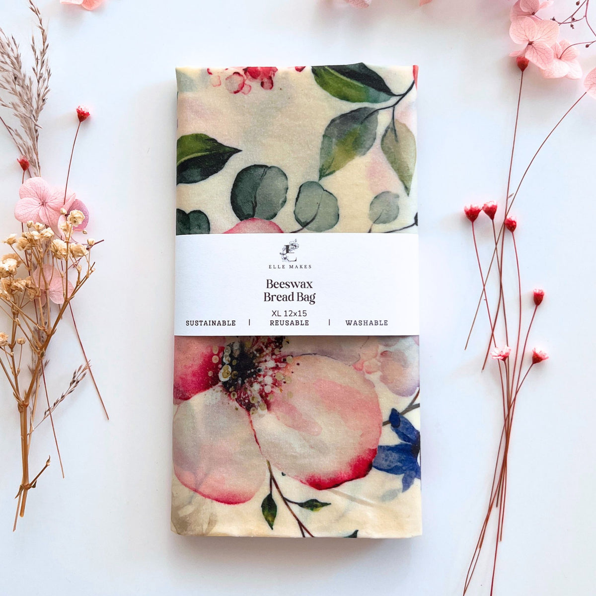 Blossom pink floral-patterned beeswax bread bag on a white background with dried flowers.