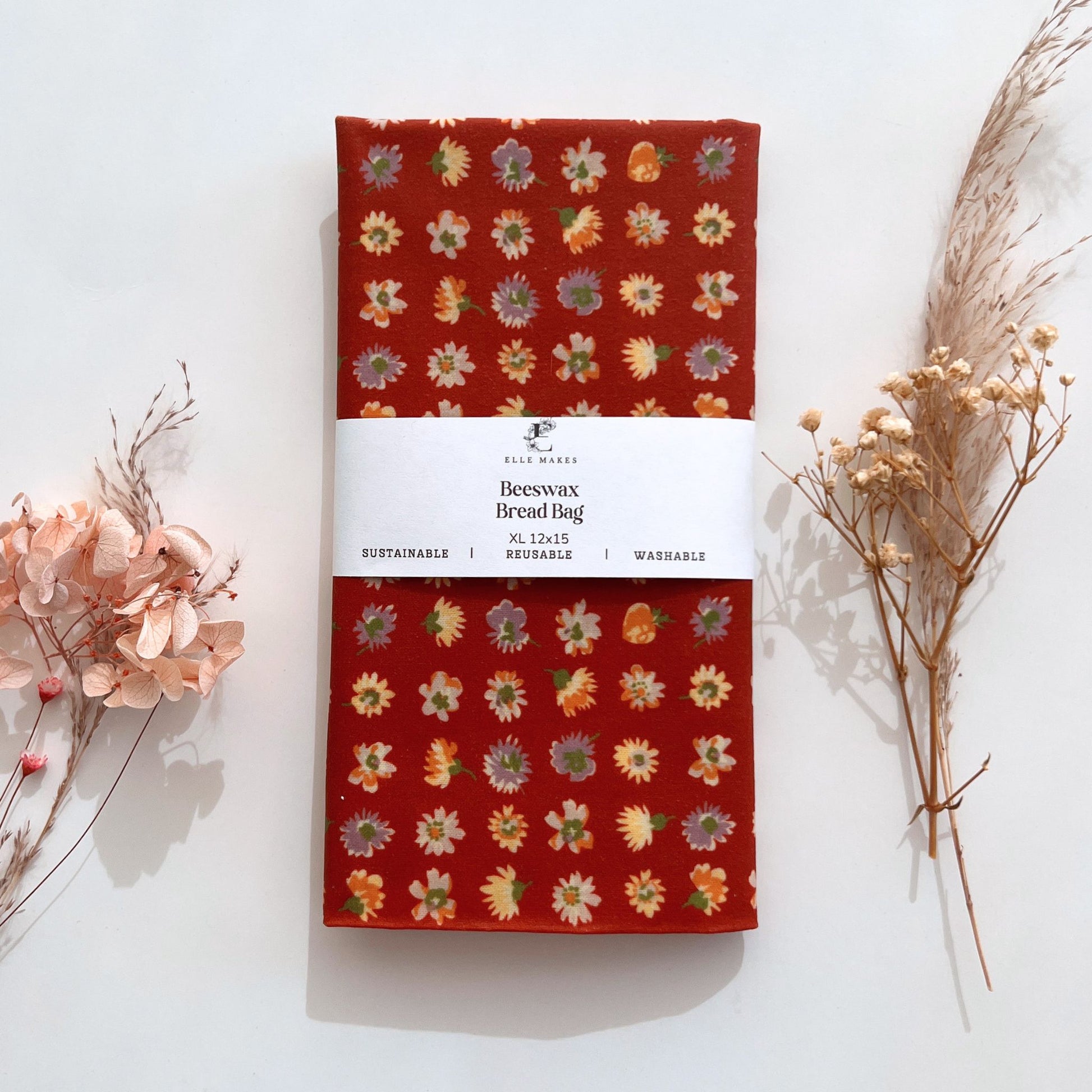 red floral-patterned beeswax bread bag packaging on a white background with dried flowers.